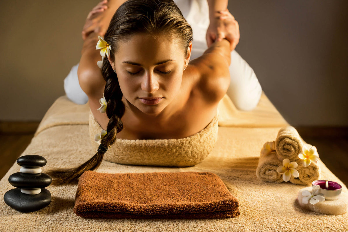 Frau erhält eine traditionelle Thai-Massage zur Dehnung und Entspannung auf einer Bodenmatte