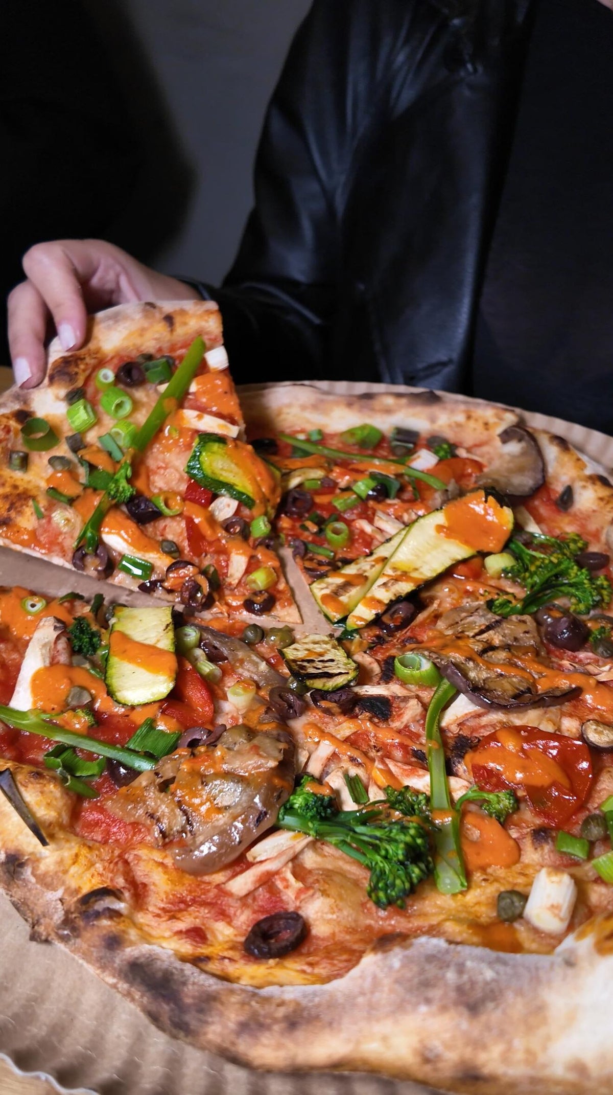 Nahaufnahme einer Pizza bei Zampano To Go Frankfurt, reichhaltig belegt mit frischem Gemüse, Paprika, Zucchini und würziger Sauce