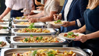 Nahaufnahme eines reichhaltigen Buffets  von ISM Foodspot in Dortmund. Mehrere Personen bedienen sich an appetitlich angerichteten Speisen.