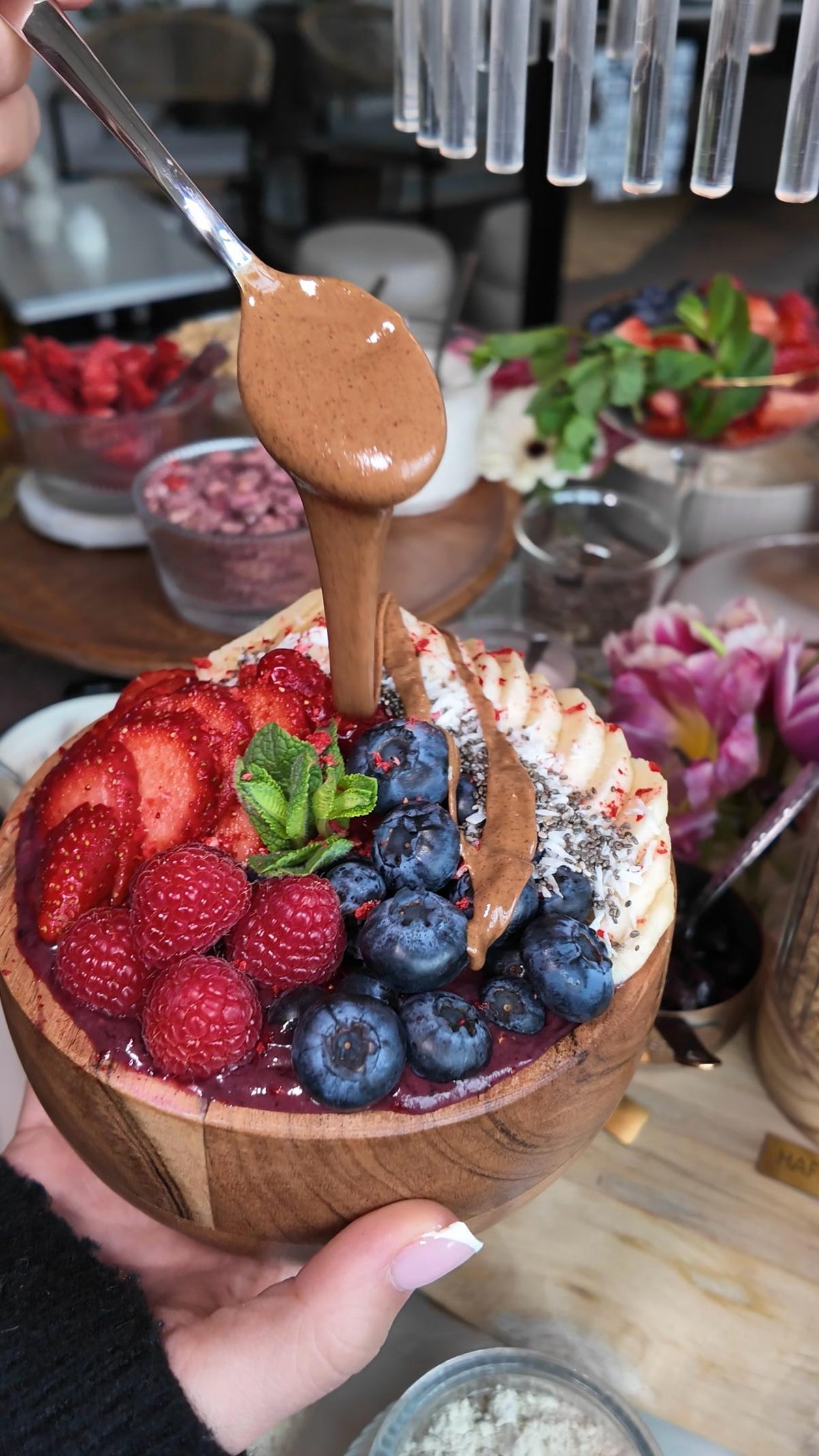 Acai-Bowl im LALA Smashburger Frankfurt mit Himbeeren, Blaubeeren, Erdbeeren, Kokosraspeln und Granola, garniert mit flüssiger Schokosauce und serviert in einer Kokosschale
