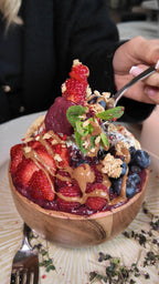 Acai-Bowl im LALA Smashburger Frankfurt mit frischen Erdbeeren, Blaubeeren, Granola, Minze, Erdnussbutter, Sorbet und Kokosflocken, angerichtet in einer Holzschale