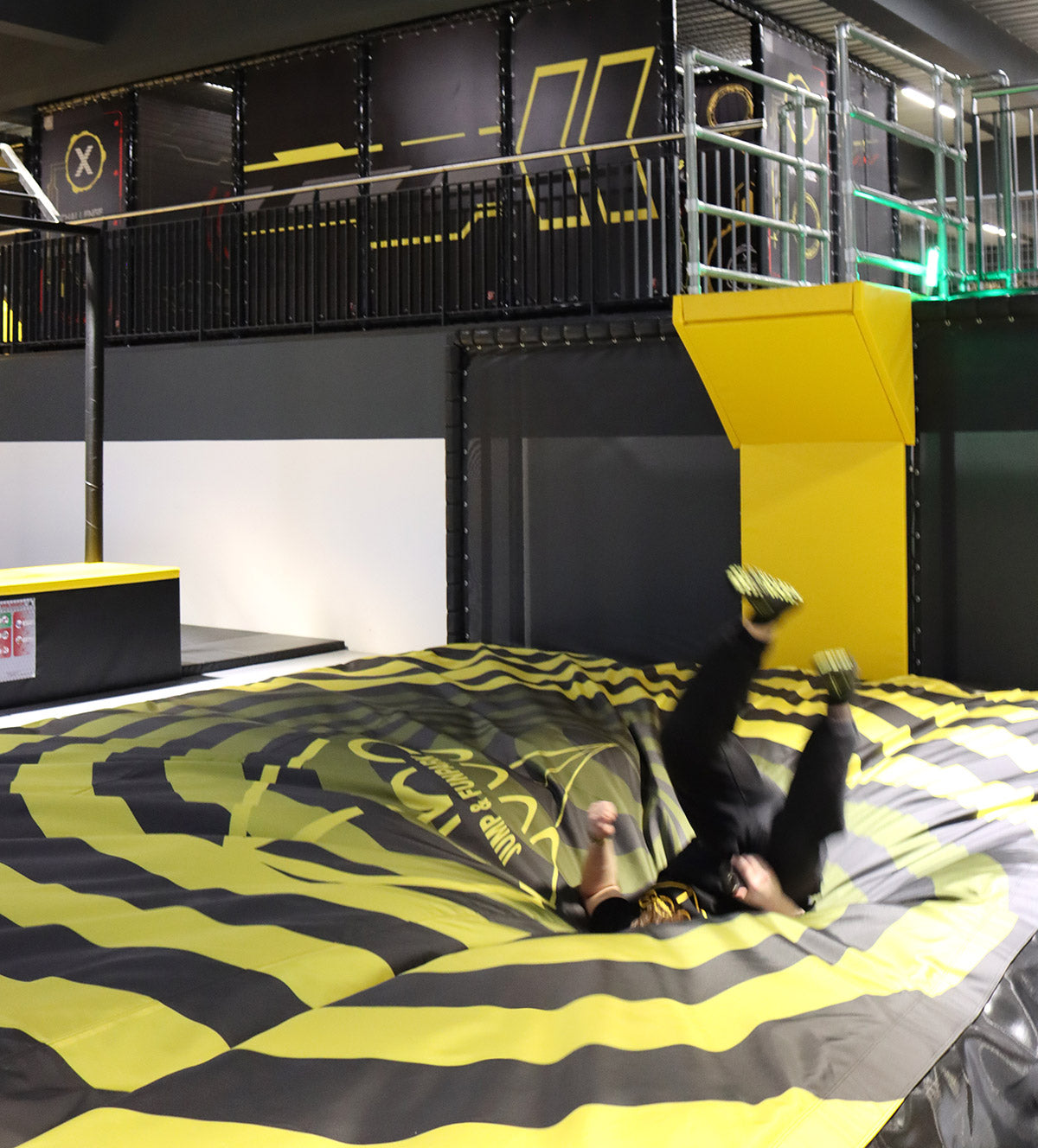 Person landet rückwärts auf einem großen Luftkissen im Cube Funpark Beselich nach einem Sprung von einer Plattform