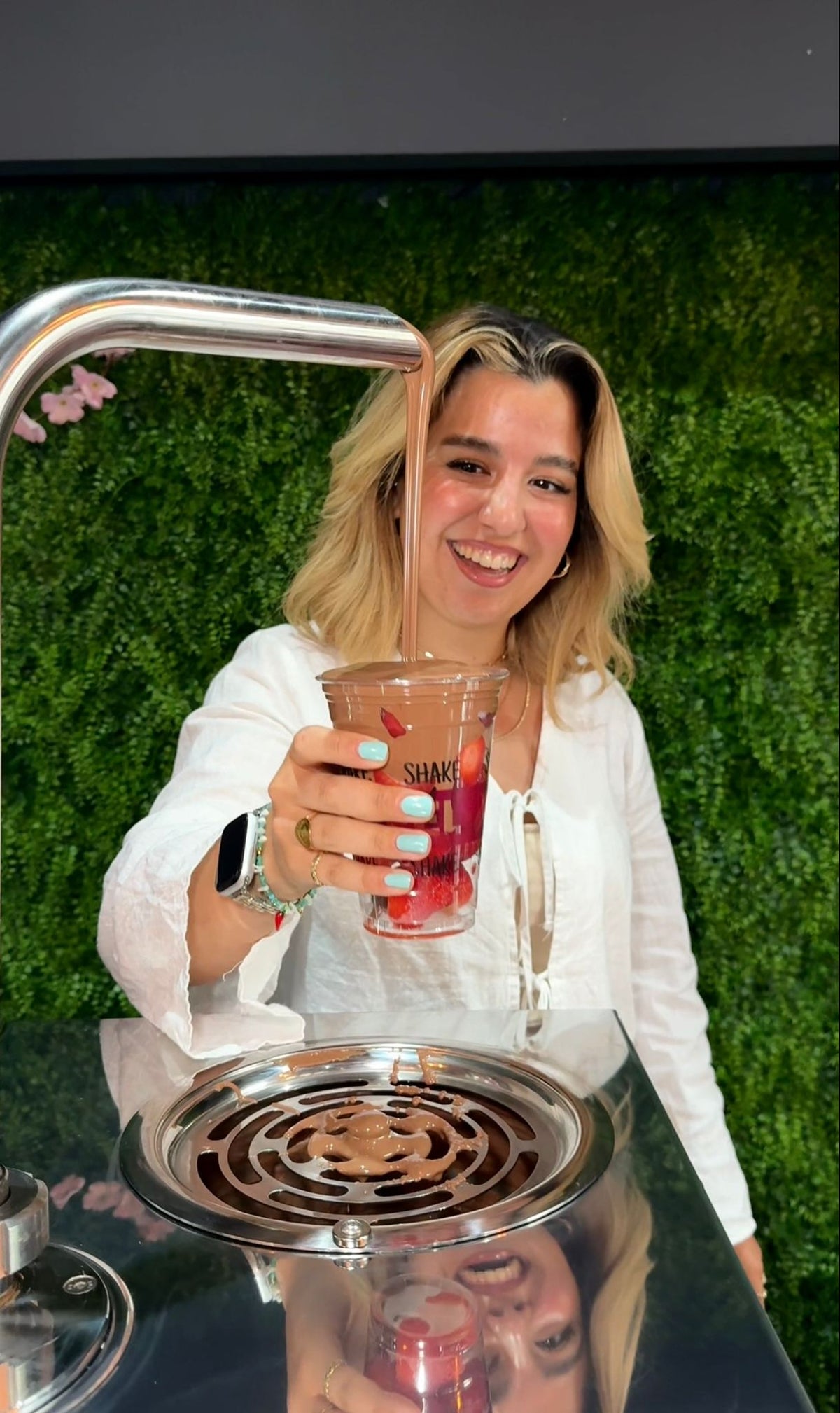 Frau hält einen Becher mit frischen Beeren unter einen Schokobrunnen bei Wonderwaffel Dortmund