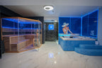Moderner Spa-Bereich in der Wellness Lounge 20° Hanau mit Infrarot-Sauna, beleuchtetem Whirlpool, blauer LED-Beleuchtung und Wandbild einer Frau mit Sonnenhut