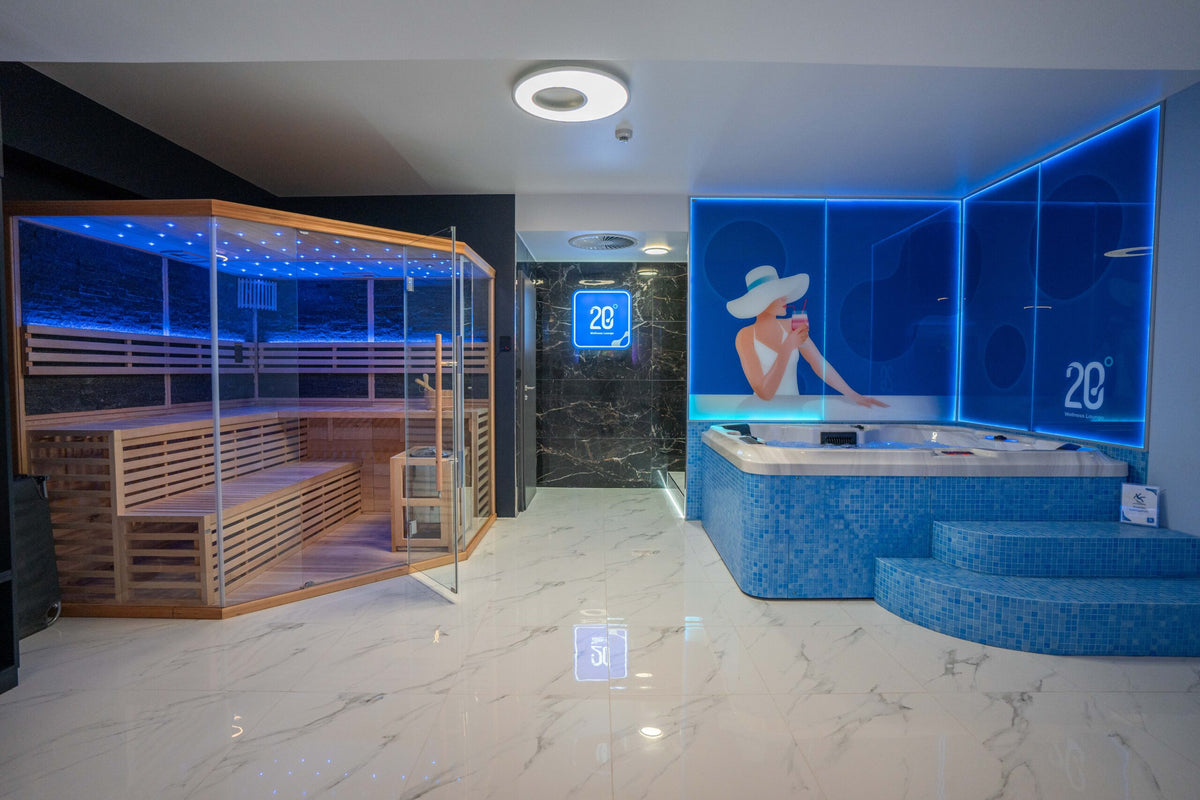 Moderner Spa-Bereich in der Wellness Lounge 20° Hanau mit Infrarot-Sauna, beleuchtetem Whirlpool, blauer LED-Beleuchtung und Wandbild einer Frau mit Sonnenhut