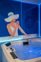 Jacuzzi-Whirlpool in der Wellness Lounge 20° Hanau vor stilisierter Wandgrafik einer Frau mit Sonnenhut und Cocktail – modern beleuchteter Spa-Bereich