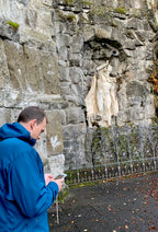 Teilnehmer der Stadtkrimis Kassel steht mit Smartphone vor einer alten Steinmauer mit historischem Relief – vermutlich im Bergpark oder nahe einer Sehenswürdigkeit