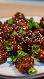 Korean Fried Chicken knusprig glasiert mit Sesam und Frühlingszwiebeln als herzhaftes Gericht bei Der Holländer in Düsseldorf.