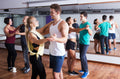 Mehrere Paare beim Salsatanzkurs im Tanzstudio, in sportlicher Kleidung vor Spiegelwand, mit lockerer und konzentrierter Stimmung