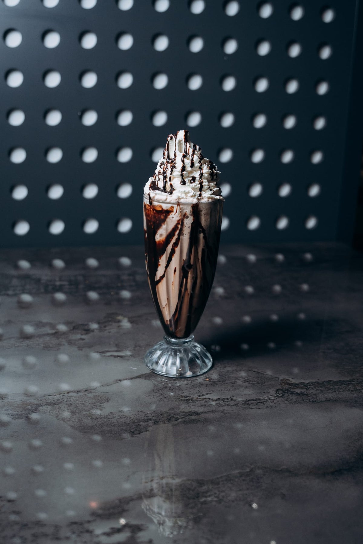 Hoher Schokoladen-Milchshake im Glas mit viel Sahne und Schokosauce, serviert im modernen Ambiente von Shiva Food and More Dinslaken