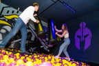 Zwei Personen stehen sich auf Plattformen in einer Schaumstoff-Arena der Face Off GmbH Rüsselsheim gegenüber und duellieren sich mit gepolsterten Stäben über einem Bällebad