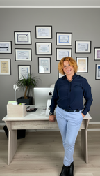 Coach steht im Büro vor Zertifikaten bei RO Coaching in München