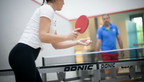Person spielt Tischtennis mit Schläger an einer Platte in der Sportinsel Taufkirchen