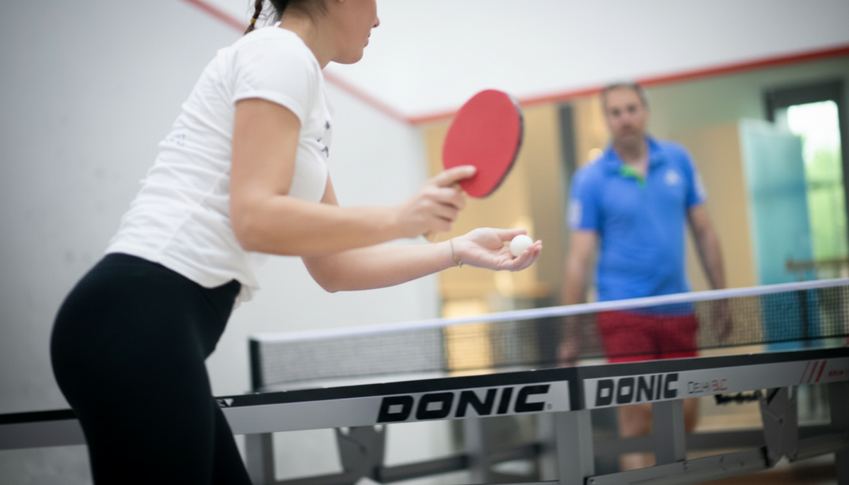 Person spielt Tischtennis mit Schläger an einer Platte in der Sportinsel Taufkirchen