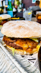 Nahaufnahme eines saftigen Burgers bei Promis Spritz Cocktail Bar Seligenstadt mit geschmolzenem Käse, frischem Brötchen und herzhaftem Belag