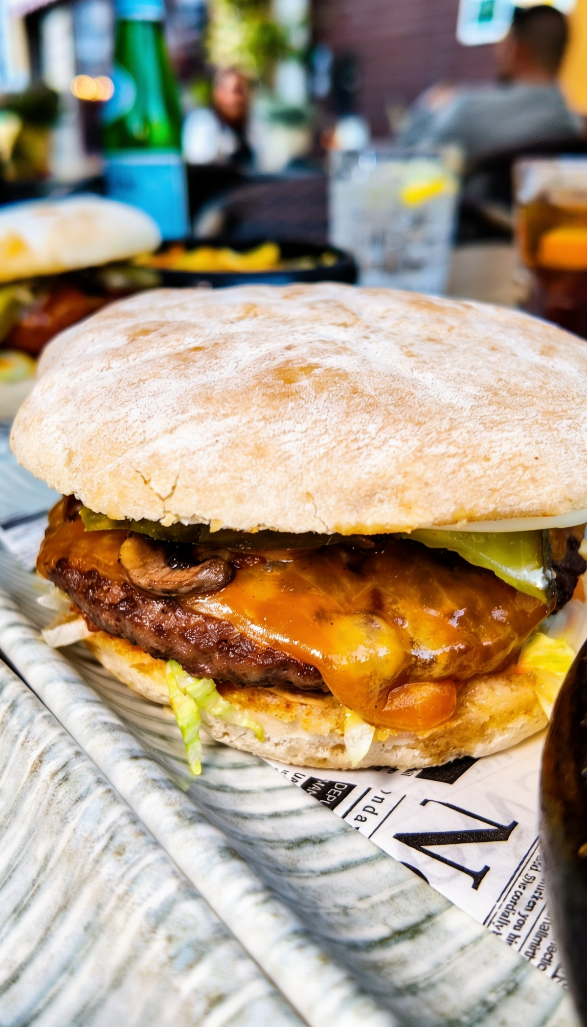 Nahaufnahme eines saftigen Burgers bei Promis Spritz Cocktail Bar Seligenstadt mit geschmolzenem Käse, frischem Brötchen und herzhaftem Belag