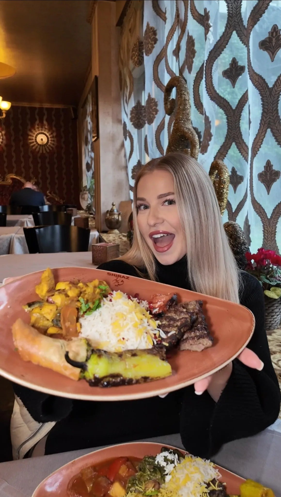 Frau hält eine große persische Grillplatte mit Reis, gegrilltem Fleisch und Gemüse im Restaurant Shiraz