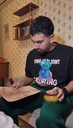 Teilnehmer im Escape Room „Muriel_Ingrid“ studiert konzentriert eine alte Karte oder ein Dokument und hält eine Urne in der Hand – Szene im Retro-Wohnzimmerstil