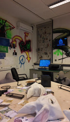 Ansicht eines Escape Rooms im Hacker-Stil bei Face Off Rüsselsheim mit Graffitis an der Wand, Computern, Kabeln, Masken und Chaos auf dem Tisch