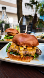 Cheeseburger beim Drei Gänge Menü im The ASH Essen – saftiger Burger mit geschmolzenem Käse, frischem Salat und knusprigen Pommes frites