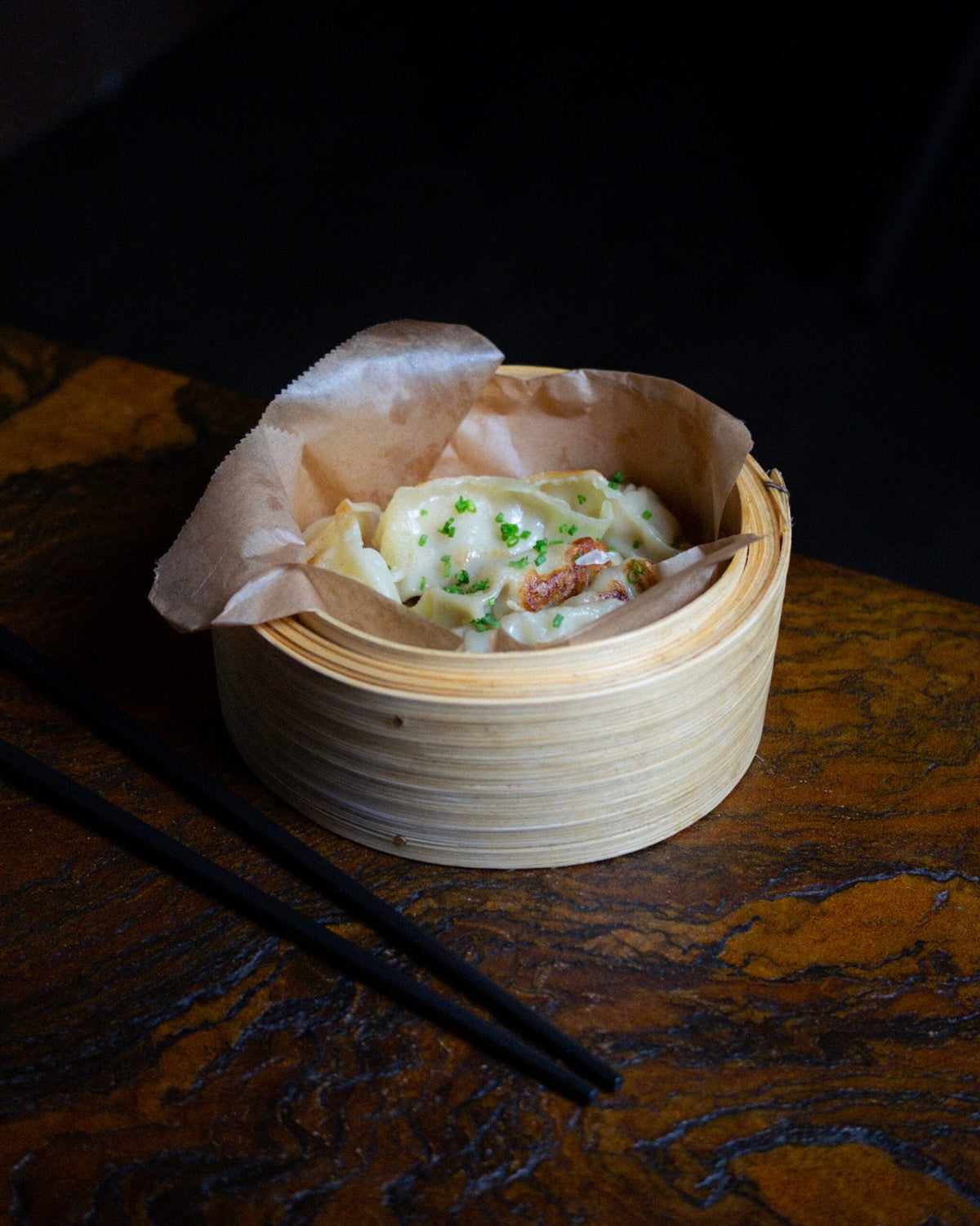 Gedämpfte Dumplings bei DUI Sushi Essen – asiatische Teigtaschen im Bambusdämpfer mit cremigem Topping