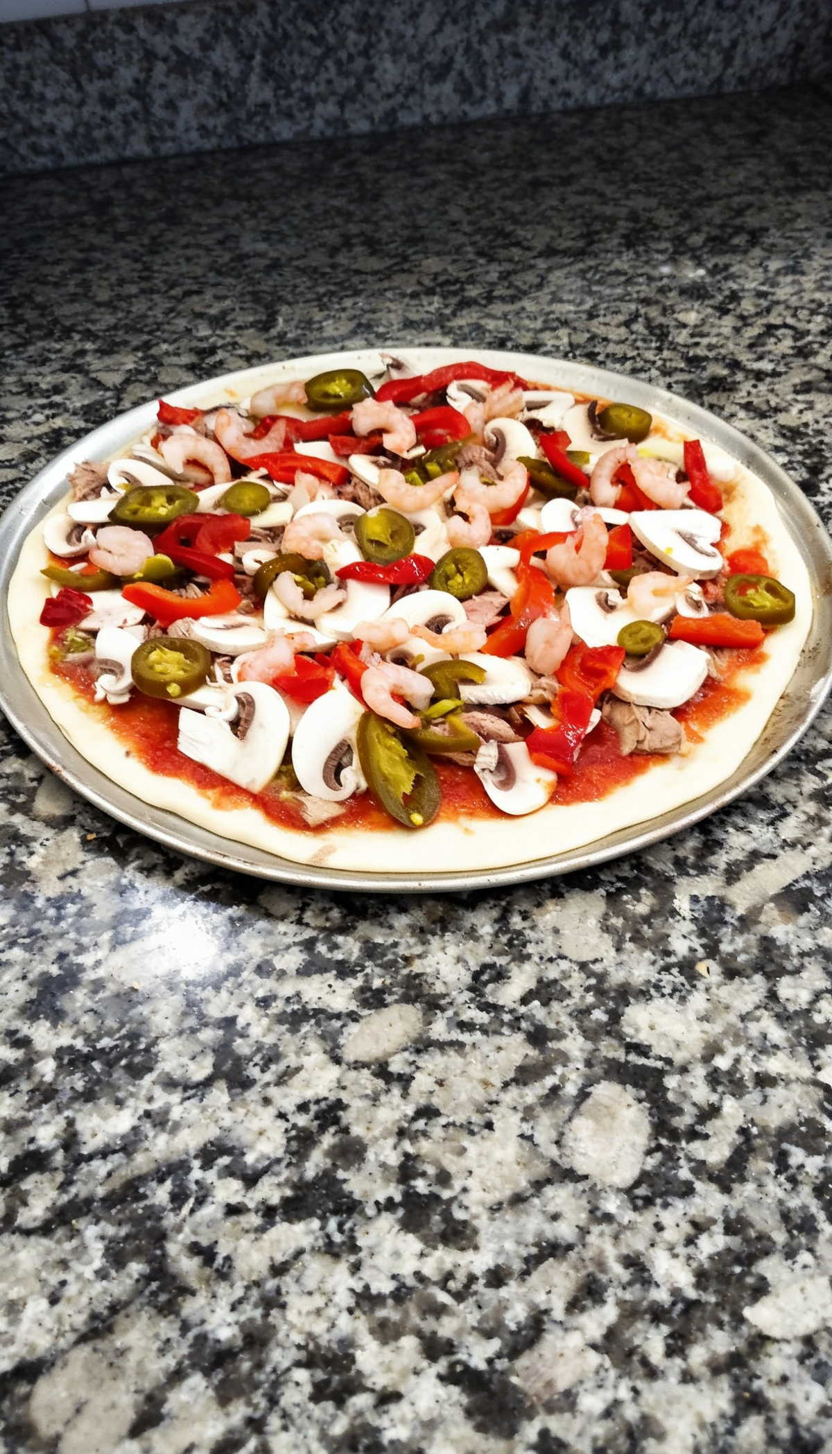 Frisch belegte Pizza bei Prados Il Siciliano Dortmund – Pizza mit Garnelen, Thunfisch, Champignons, Paprika und Jalapeños vor dem Backen