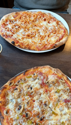 Frische Pizza Auswahl bei Pizzeria Rusticale Dortmund mit zwei belegten Pizzen auf Tellern, serviert auf einem Holztisch