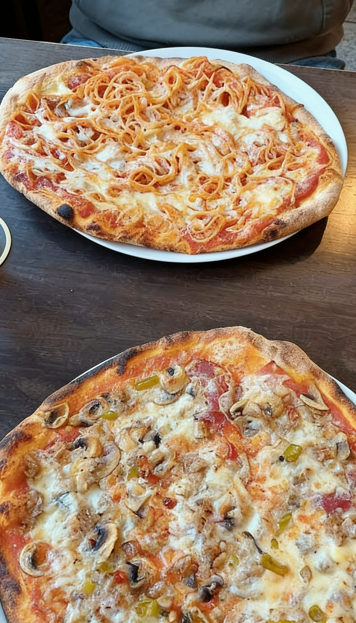 Frische Pizza Auswahl bei Pizzeria Rusticale Dortmund mit zwei belegten Pizzen auf Tellern, serviert auf einem Holztisch