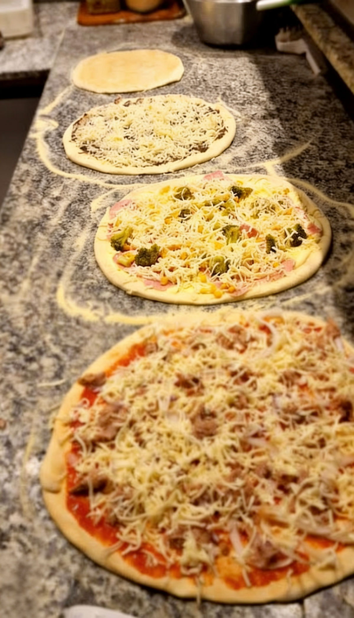 Frisch belegte Pizzen bei Pizzeria Rusticale Dortmund während der Zubereitung auf einer bemehlten Arbeitsfläche