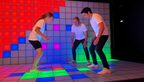Gruppe im Pixel Room bei Room Escape Frankfurt, während sie auf einem leuchtenden Spielfeld gemeinsam ein interaktives Erlebnis spielt