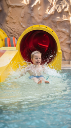 Kind rutscht im Aqualand Köln aus einer Wasserrutsche ins Becken – actionreicher Wasserspaß im Erlebnisbad für die ganze Familie