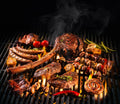 Verschiedene Fleischsorten wie Steaks, Rippchen, Würste sowie Gemüse und Spieße brutzeln auf einem heißen Grillrost