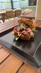 Brioche Sandwich bei Coal and Bean in Essen mit frischem Salat, cremigem Belag und herzhaften Zutaten auf einem schwarzen Teller serviert