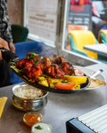 Frisch dampfendes Tandoori-Gericht mit Gemüse wird in einer heißen Pfanne im Sweet Laddu Köln am Tisch serviert