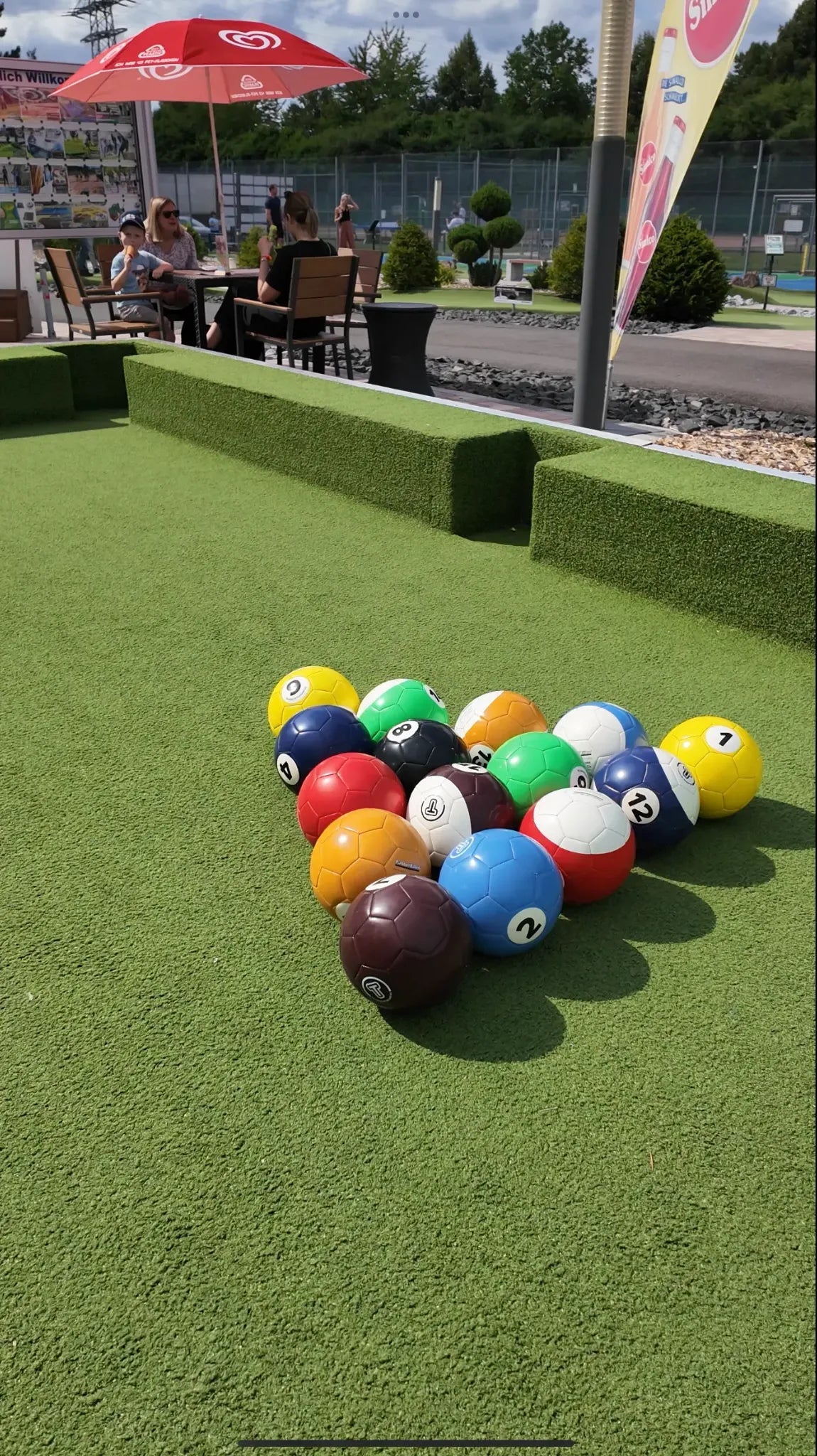 Bunte Bälle in Dreiecksformation auf einem großen Outdoor-Soccer-Billard-Feld mit Kunstrasen