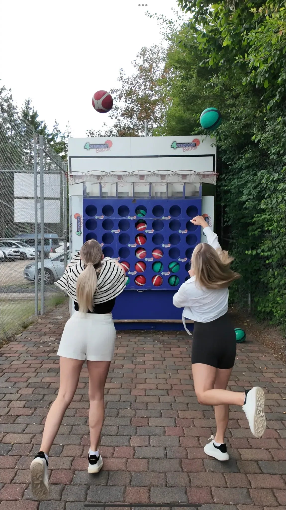 Zwei junge Frauen werfen Bälle auf eine große bunte Reaktionswand im Freien auf dem Sport- und Freizeitpark in  Limburg-Linter