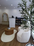 Heller und modern eingerichteter Empfangsbereich von Elli Beauty in Frankfurt mit runder Couch, Holzdetails und Pflanze