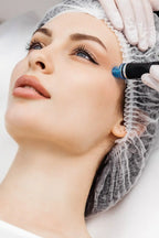 Frau mit Haarnetz bekommt eine Aquafacial-Behandlung mit einem blauen Applikatorkopf im Stirnbereich, durchgeführt von einer Kosmetikerin mit Handschuhen
