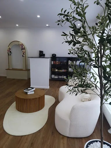 Heller und modern eingerichteter Empfangsbereich von Elli Beauty in Frankfurt mit runder Couch, Holzdetails und Pflanze