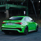 Audi RS3 Limousine in auffälligem Neongrün, fotografiert von hinten in einem Industrieumfeld