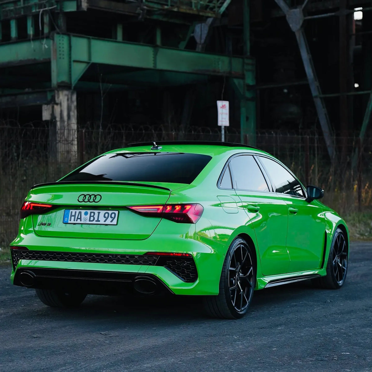 Audi RS3 Limousine in auffälligem Neongrün, fotografiert von hinten in einem Industrieumfeld