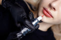 Detailaufnahme einer Lippenpigmentierung mit Permanent Make-up – die Farbe wird präzise mit einer Maschine aufgetragen