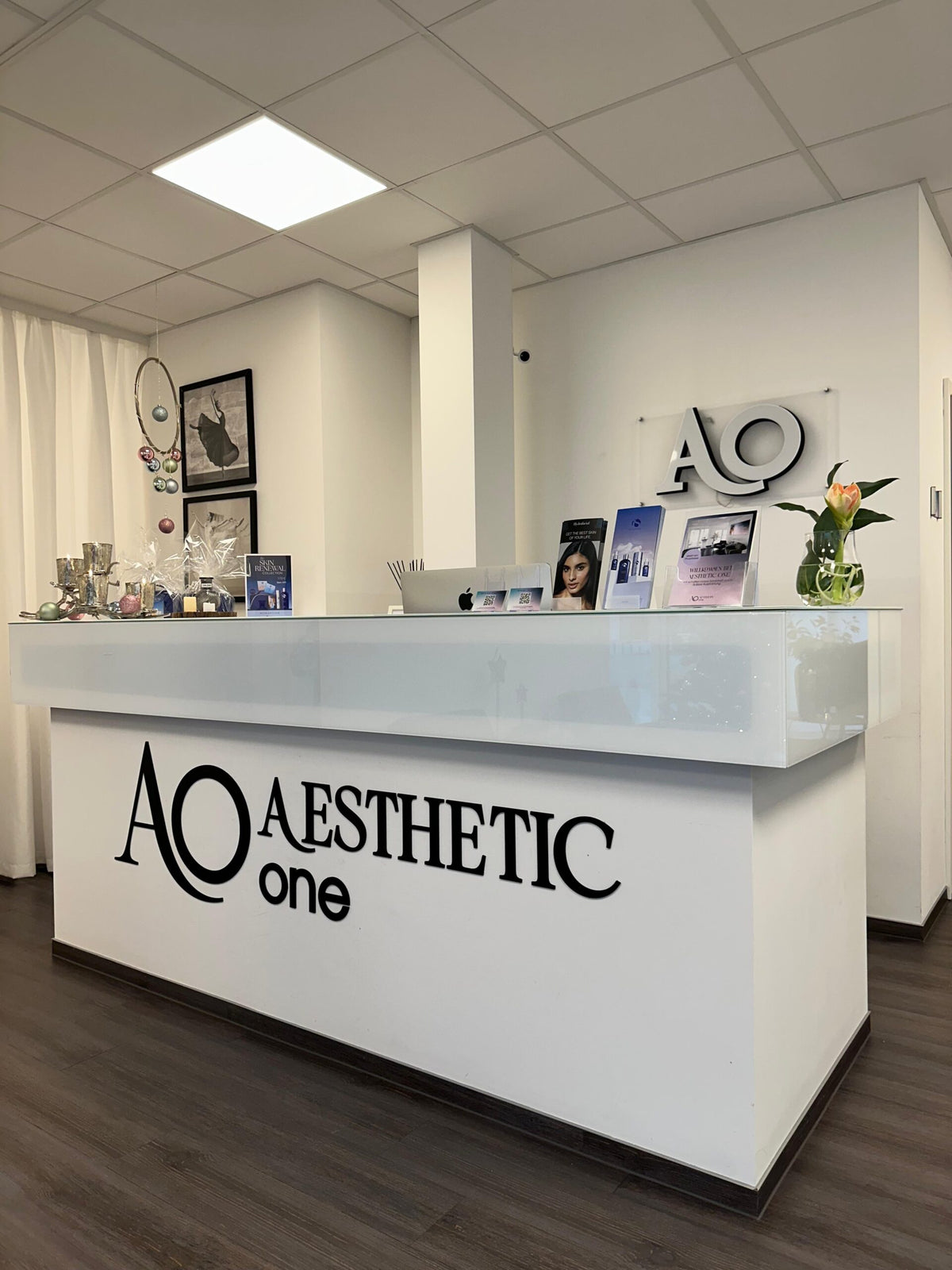 Moderner Empfangsbereich von Aesthetic One in Dortmund mit weißem Tresen und dekorativen Elementen