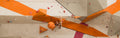 Kletterer an einer orangen Boulderwand mit verschiedenen Griffen im Sportpoint Meckenheim