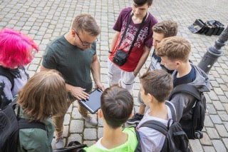 Gruppe Jugendlicher mit Tablet bei einem Outdoor Escape Game von Frankfurt Secrets – Magisches Portal