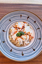 Manti mit Joghurt und Paprikabutter, serviert auf einem dekorativen Teller