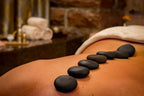 Hot-Stone-Massage mit schwarzen Lavasteinen in einer stimmungsvollen Wellnessumgebung