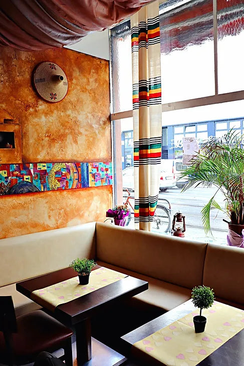 Bunter, gemütlicher Fensterplatz mit ethnischem Wanddesign im Adabina Restaurant Frankfurt