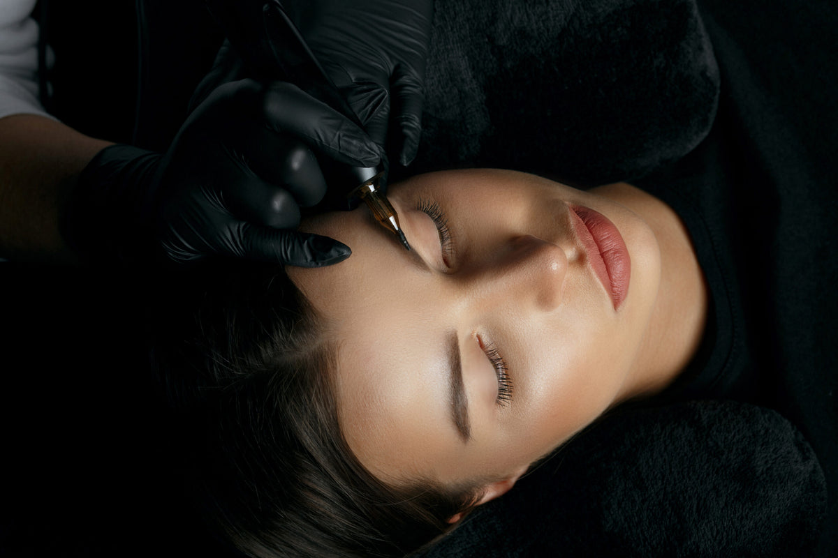Frau mit geschlossenen Augen während einer Microblading-Behandlung in stilvoller Atmosphäre