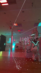 Person in VR-Ausrüstung weicht virtuellen Lasern in futuristischer Spielarena in Berlin aus.
